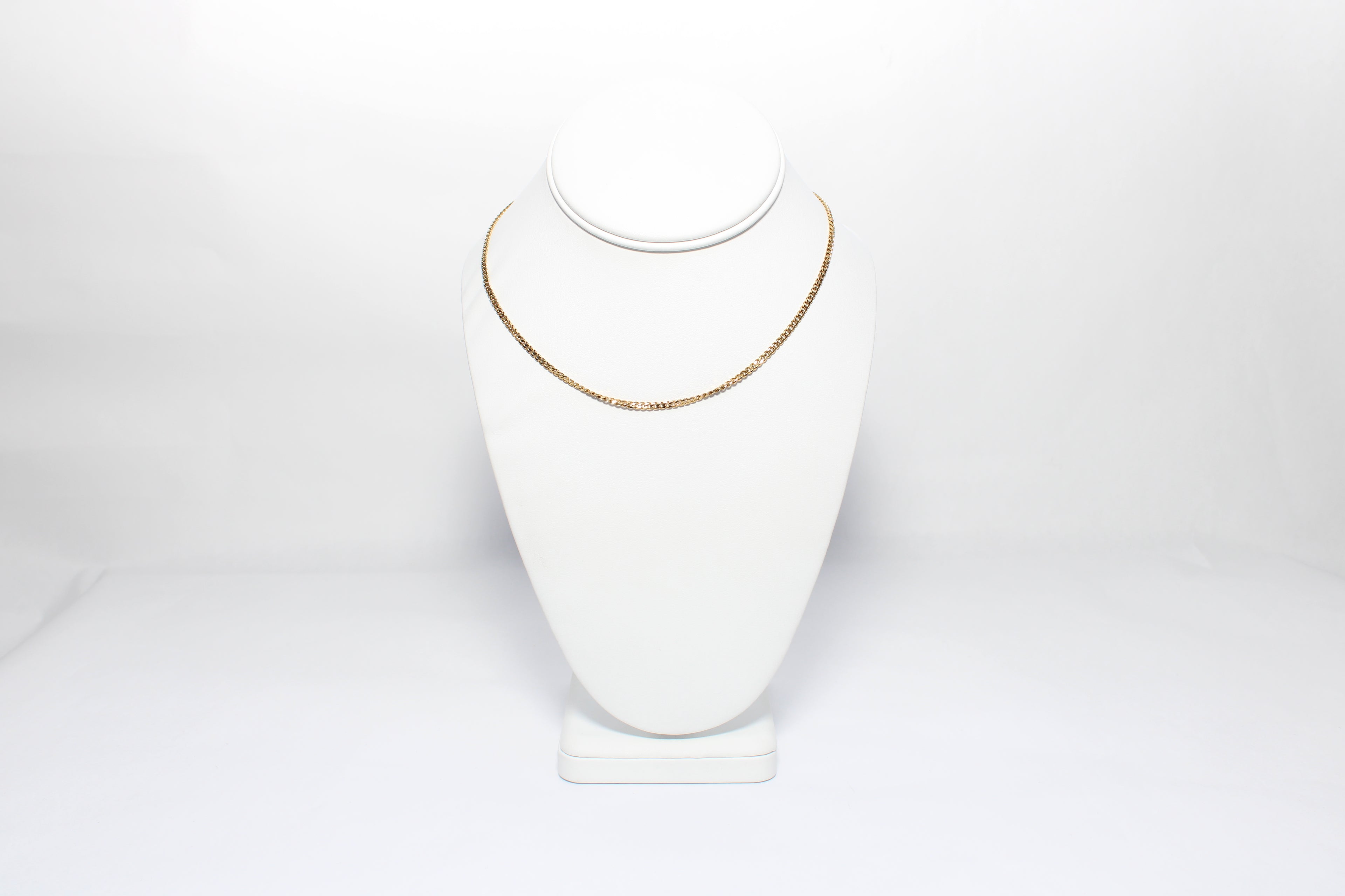 Gold necklace on a white mannequin bust against a white background