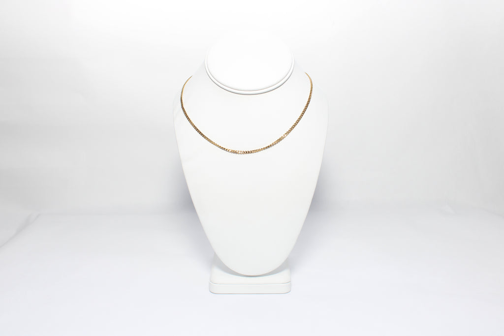 Gold necklace on a white mannequin bust against a white background